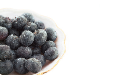 ripe big  blueberries in the plate around white white background close-up