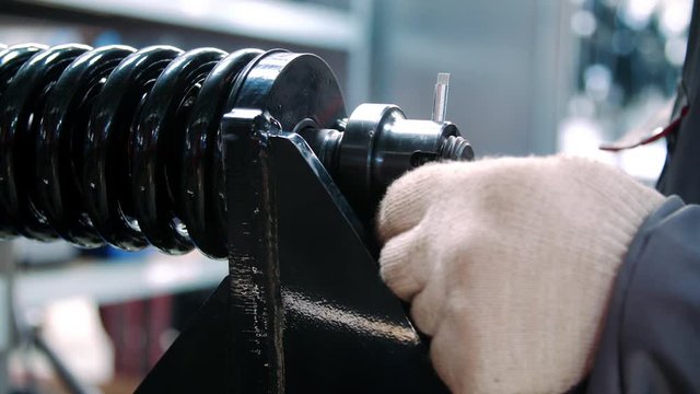 Worker fixing black spring during assembly shock absorber at industrial plant