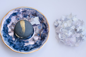  Top view on gray-blue macaroon with butter cream on mother of pearl porcelain plate with...