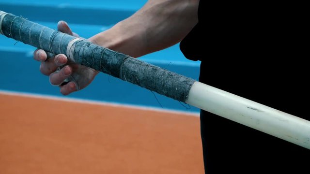 Hands holding sports equipment. Athlete preparing to jump in height with pole