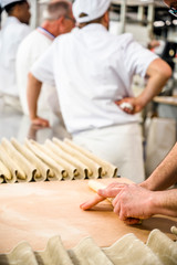 Baker rolls dough for French baguettes