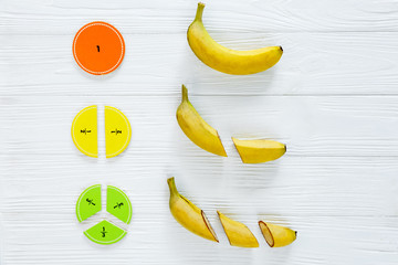 Сolorful math fractions and bananas as a sample on white wooden background or table. Interesting...