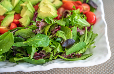 Natural vegetable salad from green leaves and tomato and avocado rich in vitamins and fiber is...