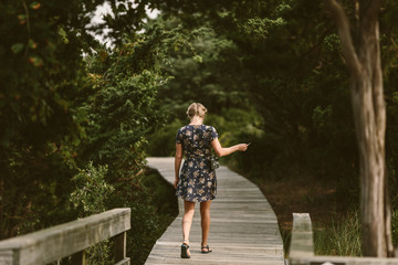 woman walking down a tree-lined boardwalk