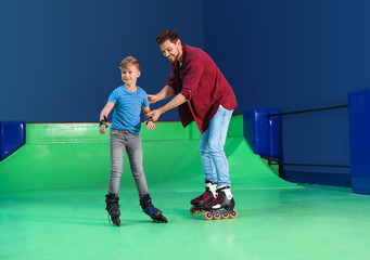 Father teaching his son roller skating at rink