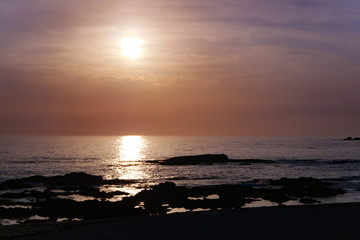Fototapeta na wymiar Sun reflected on ocean at sunset with pink sky