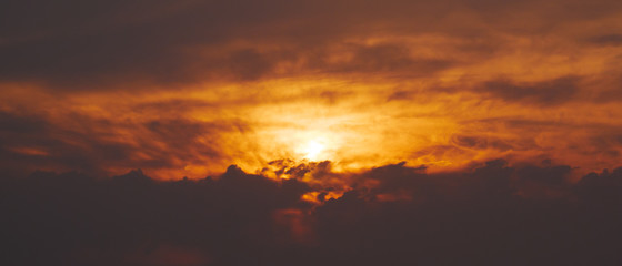 Vivid orange sunset sky with dark, dramatic clouds.