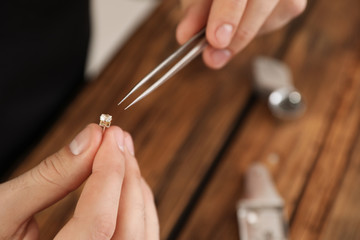Male jeweler evaluating earring at table in workshop, closeup