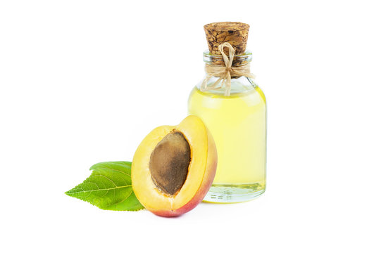 Glass bottle of apricot kernel oil with half Fresh Ripe apricot fruit and leaf isolated on white background with clipping path