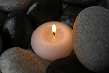 Obraz na płótnie Canvas Beautiful burning candle and smooth stones