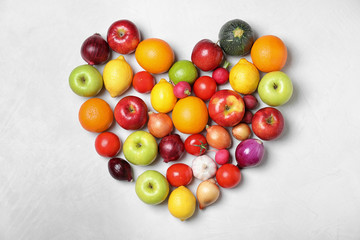 Heart shaped pile of fruits and vegetables on light background, flat lay