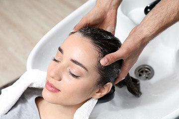 Stylist washing client's hair at sink in beauty salon