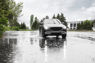 Modern car driving outdoors on rainy day