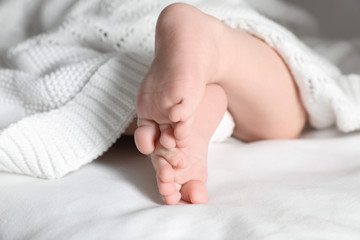 Little baby with cute feet lying on bed, closeup