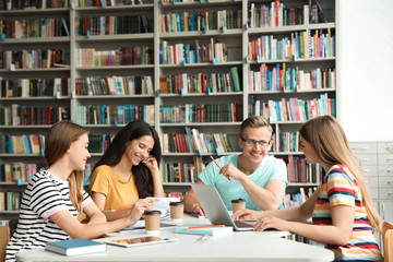 Young people discussing group project at table in library