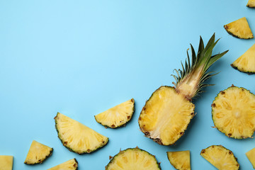 Flat lay composition with cut and fresh juicy pineapples on color background, space for text
