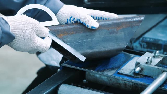 Engineer measuring angles of metal blank by protractor angle finder