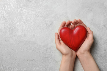 Woman holding heart on grey stone background, top view with space for text. Donation concept