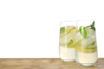 Glasses of refreshing lemonade on wooden table against white background, space for text. Summer drink
