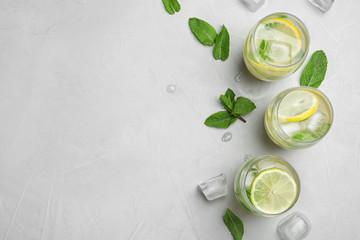 Flat lay composition with glasses of refreshing lemonade on grey background, space for text. Summer drink