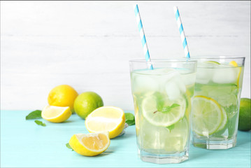 Glasses of refreshing lemonade on light blue table, space for text. Summer drink