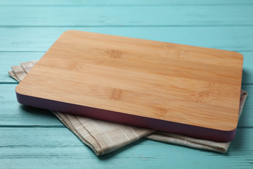 Wooden board and beige kitchen towel on blue table