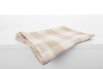 Folded kitchen towel on light table against white background