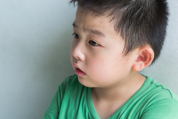 Cute boy in green shirt feel sad and tired from crying, close up portrait