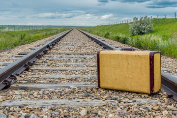 Vintage suitcase in the middle of railroad tracks on the prairies