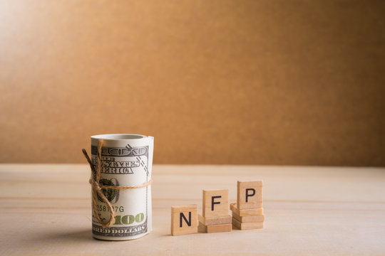 Non-farm payrolls (NFP) Conceptual image with a roll of 100 American Dollar USD on wooden base