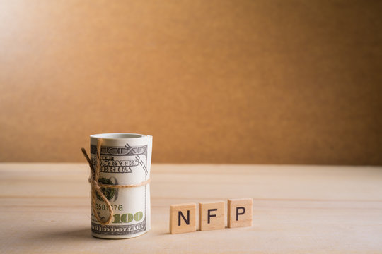 Non-farm payrolls (NFP) Conceptual image with a roll of 100 American Dollar USD on wooden base