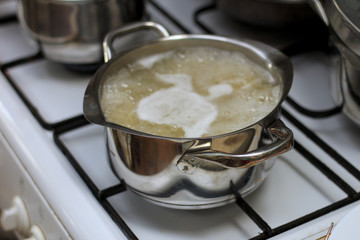large shiny metal pan on the stove with sugar syrup boiling in it