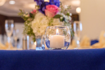 Glass round candle holder with lit white candle