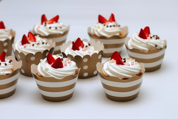 Close-up cupcakes with whipped eggs cream decorated fresh strawberry and chocolate balls on white background. Isolate