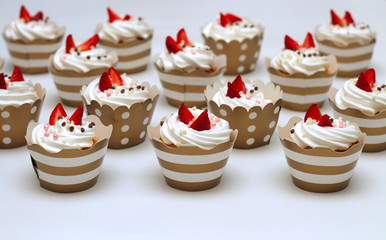 Close-up cupcakes with whipped eggs cream decorated fresh strawberry and chocolate balls on white background. Isolate