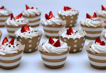 Close-up cupcakes with whipped eggs cream decorated fresh strawberry and chocolate balls on white background. Isolate