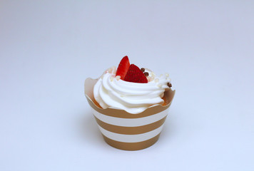 Close-up cupcake with whipped eggs cream decorated fresh strawberry and chocolate balls on white background. Isolate