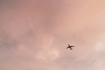 An airplane in flight against rainbow colorful sky and clouds. Abstract pastel beautiful landscape at sunset.