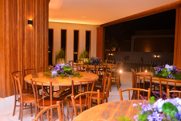 ballroom with wooden tables and chairs decorated with flowers, table and chairs in cafe, wooden tables and chairs for party room