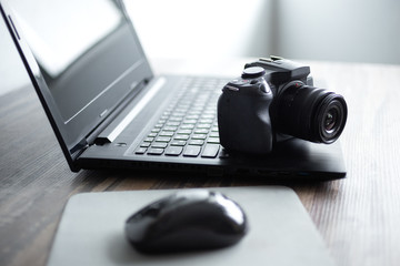 Fototapeta na wymiar Photographer or stock photography concept, digital black camera near laptop on desk workstation