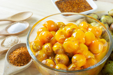 Ceylon oak in glass bowl peel reveal appetizing orange fruit on wood table. thai fruit. Schleichera oleosa (Lour.) Oken. Nephelium hypoleucum. Sapindaceae. Livistona speciosa.