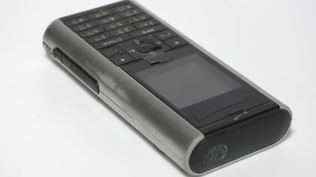 An old mobile phone with keypad on the surface moving