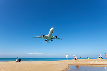 Fototapeta na wymiar Airplane landing above beautiful beach and sea background