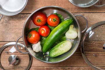 cooking pot with fresh organic vegetables. tomatoes with cucumbers and onion