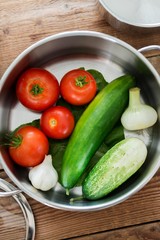 cooking pot with fresh organic vegetables. tomatoes with cucumbers and onion