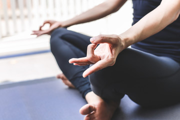 Young woman practicing yoga in  gray background.Young people do yoga indoor.Close up hands in meditating gesture. Copy space.