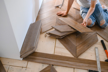 Man laying parquet flooring - closeup on male hands. worker joining parquet floor
