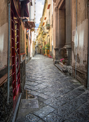 Fototapeta na wymiar Charming, empty, narrow, cobbled street lined with old, stone buildings in Italy