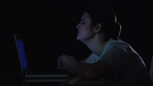 Teenager girl crying because of problems with laptop, sitting in dark room