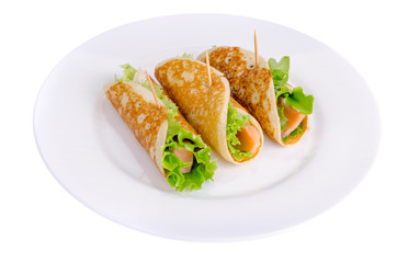 Snack rolls from pancakes, salmon and green salad leaves. 
